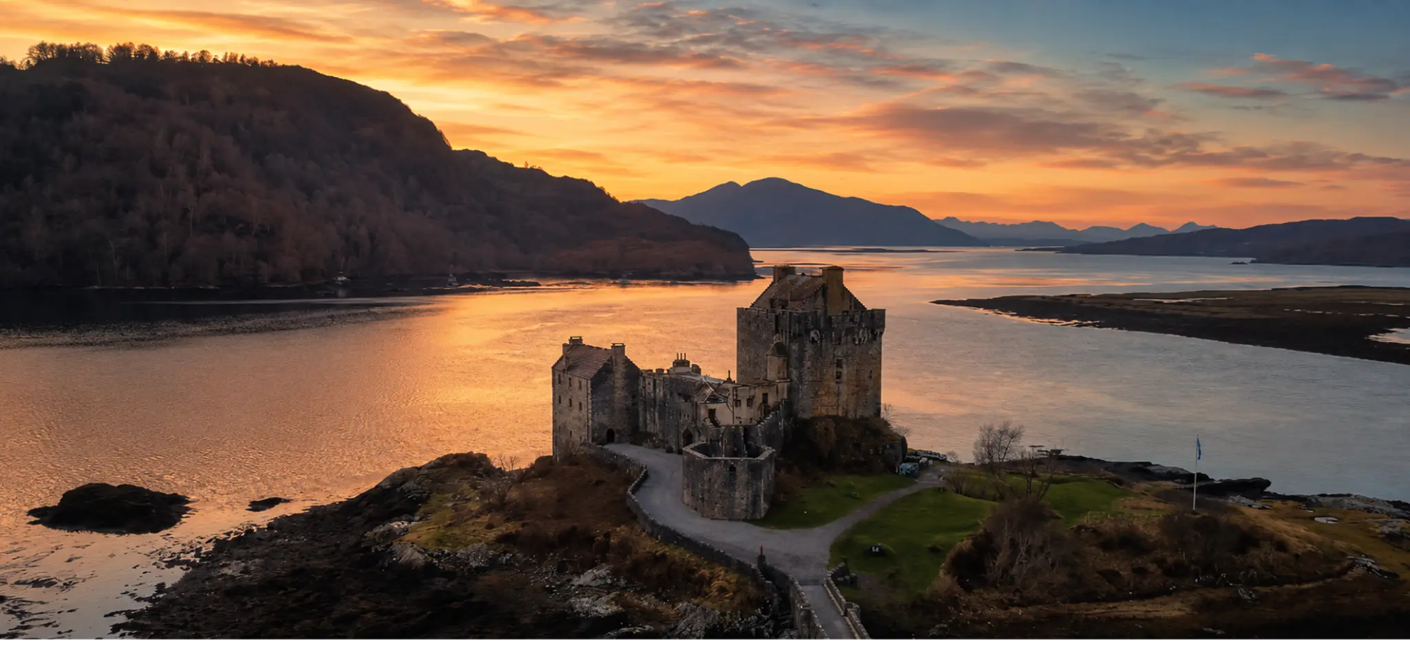 Highland castle and loch beneath a warm sunset