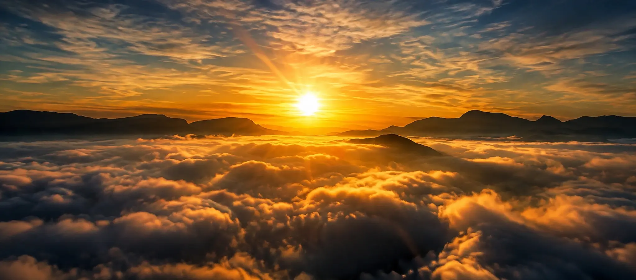Golden sunrise above a mountain cloud inversion