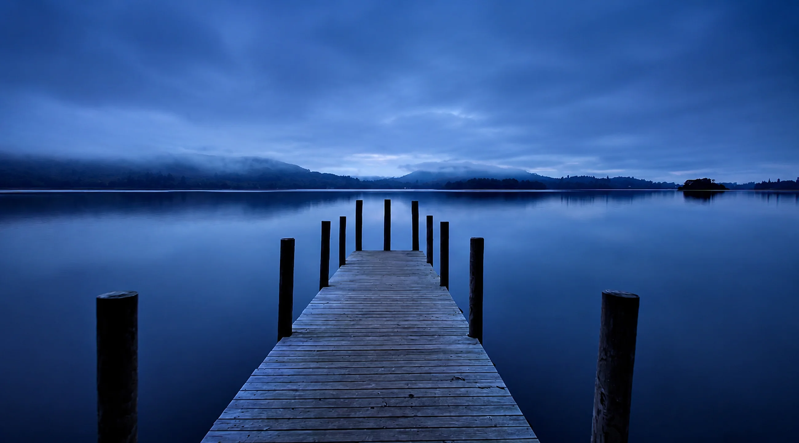 A still jetty reaching into the lake at blue hour